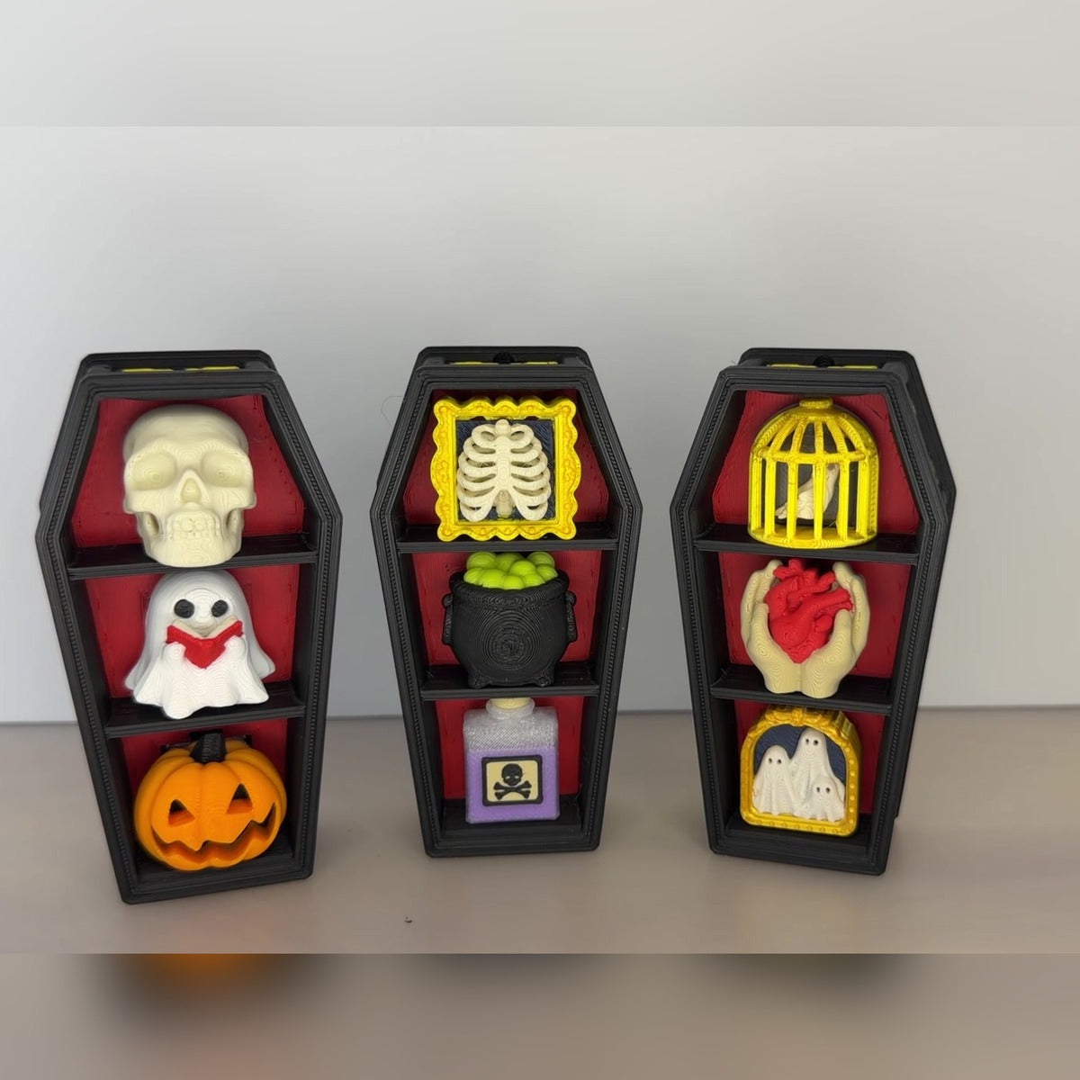 Three gothic coffin clickers with skull, ghost, pumpkin, ribcage, cauldron, birdcage and heart keycaps